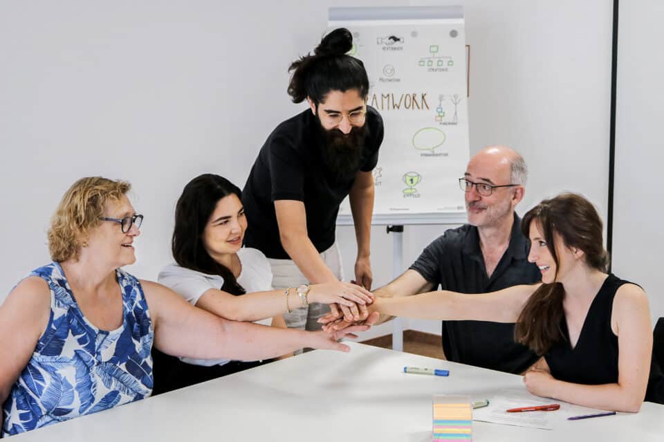 Fünf Kolleg*innen legen ihre Hände aufeinander.