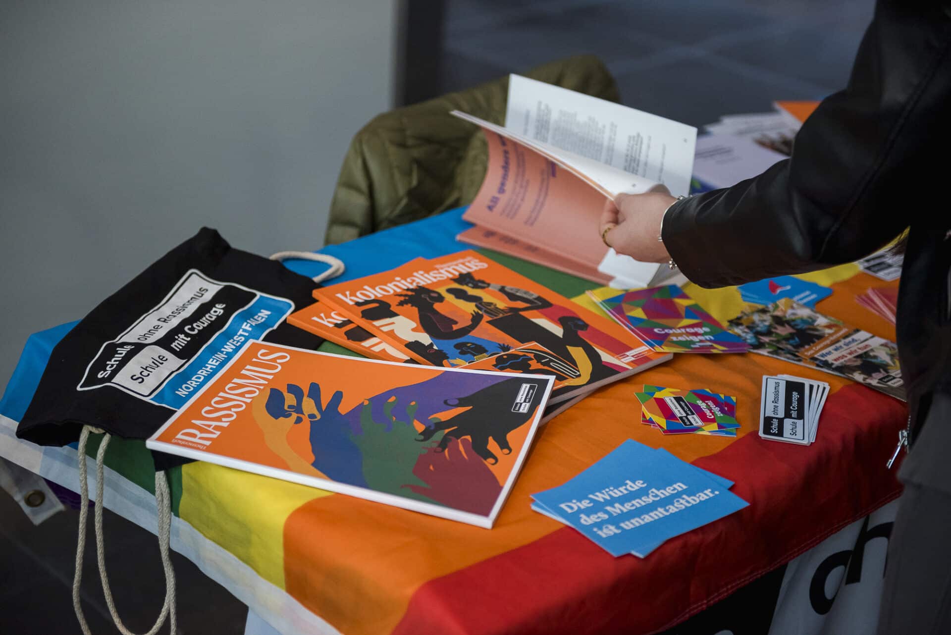 Auf einem Tisch liegen Broschüren und Merch-Artikel des Netzwerks "Schule ohne Rassismus - Schule mit Courage".