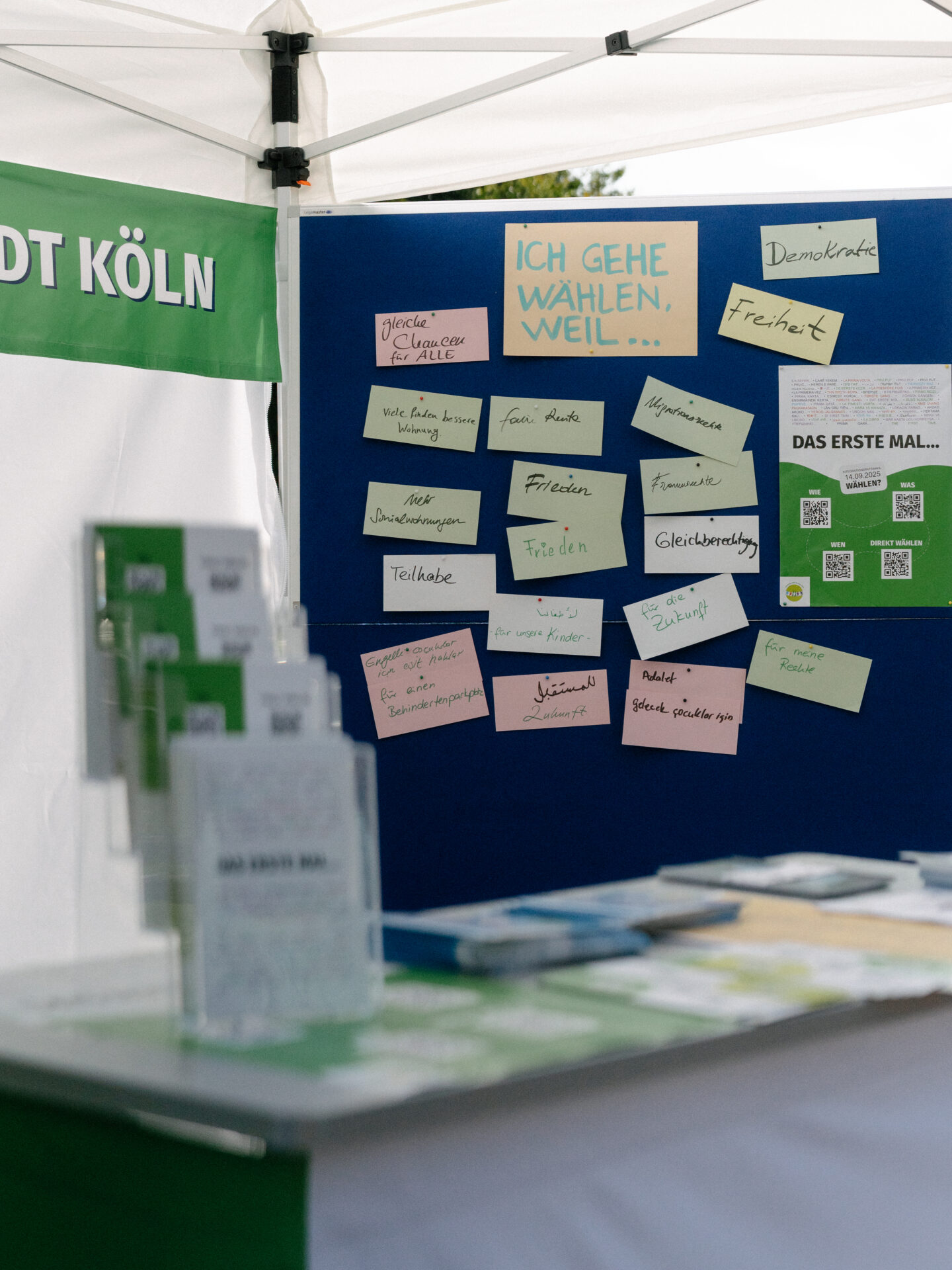 Das Foto zeigt einen Informationsstand. Auf einem Tisch liegen Flyer. An einer Pinnwand sind Karten mit Gründen, wählen zu gehen, aufgehängt.